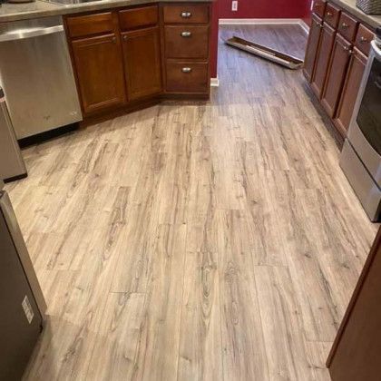 Kitchen with wooden cabinets, stainless steel appliances, and light-colored wood-look flooring.