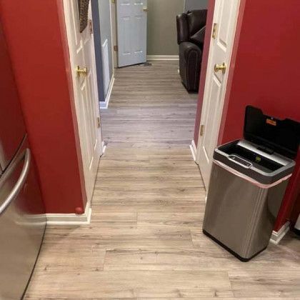 Hallway with light wood-look floor. Red walls, white doors. Stainless steel trash can on the right. 