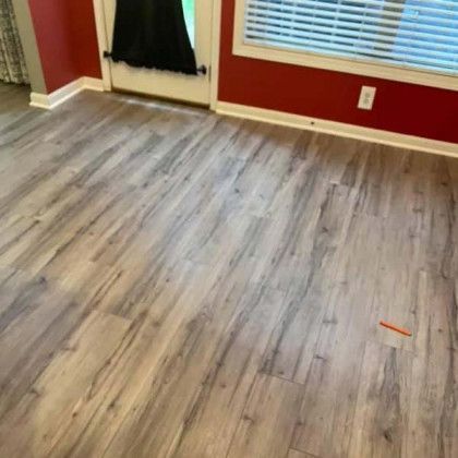 Wooden plank flooring in a room with red walls, a door, and a window with blinds.