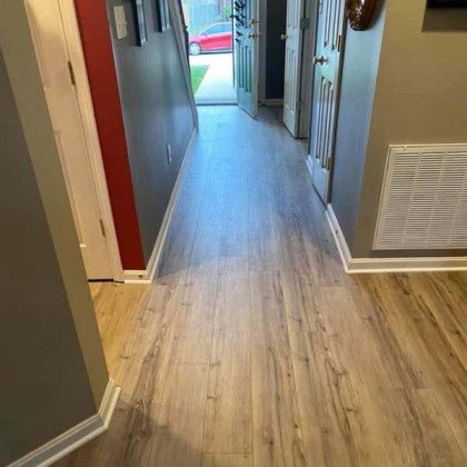 Hallway with wood-look flooring, neutral walls, and a red accent wall. Doors and a vent are also visible.