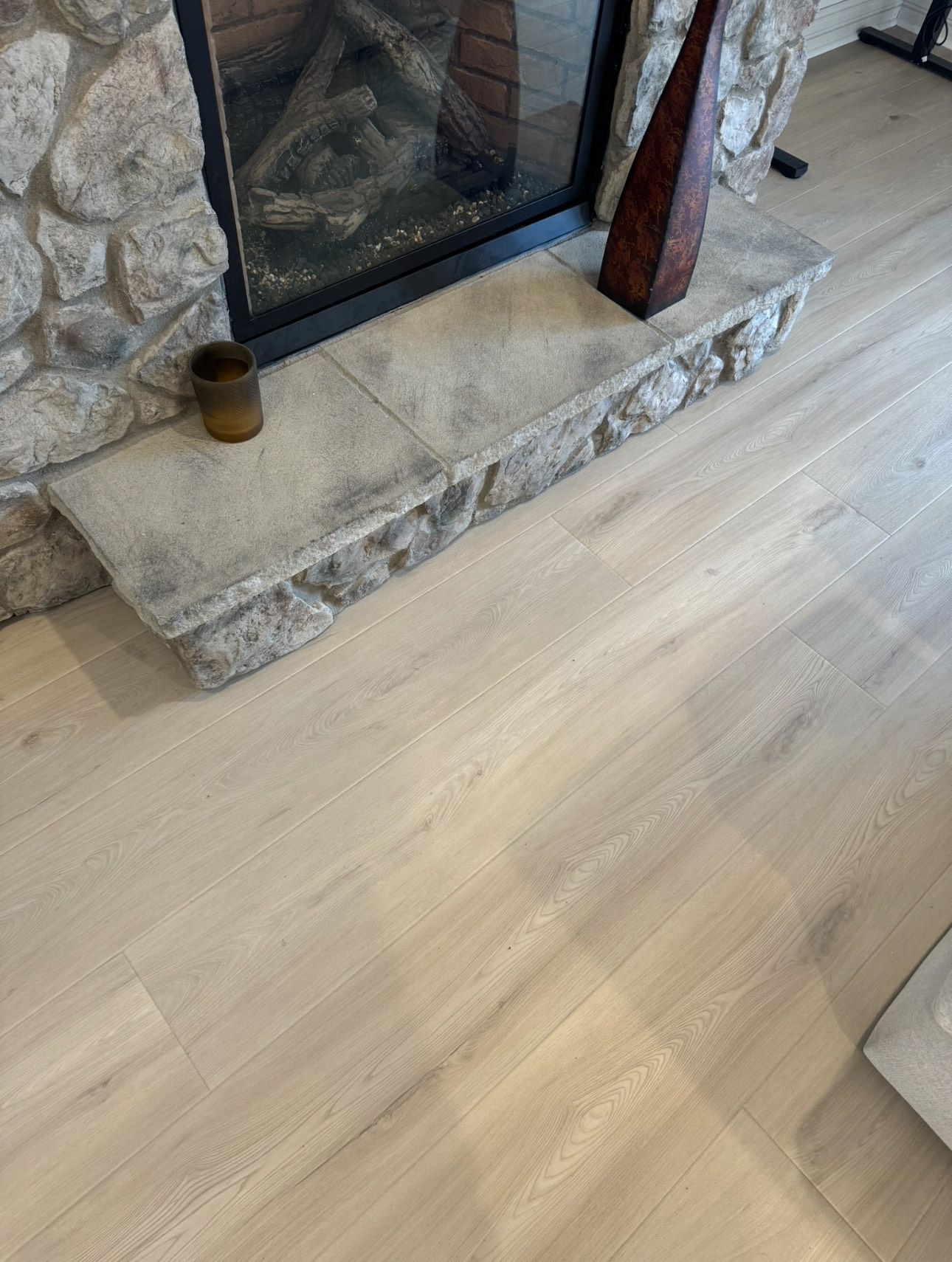 Light wood floor with a stone fireplace and hearth.