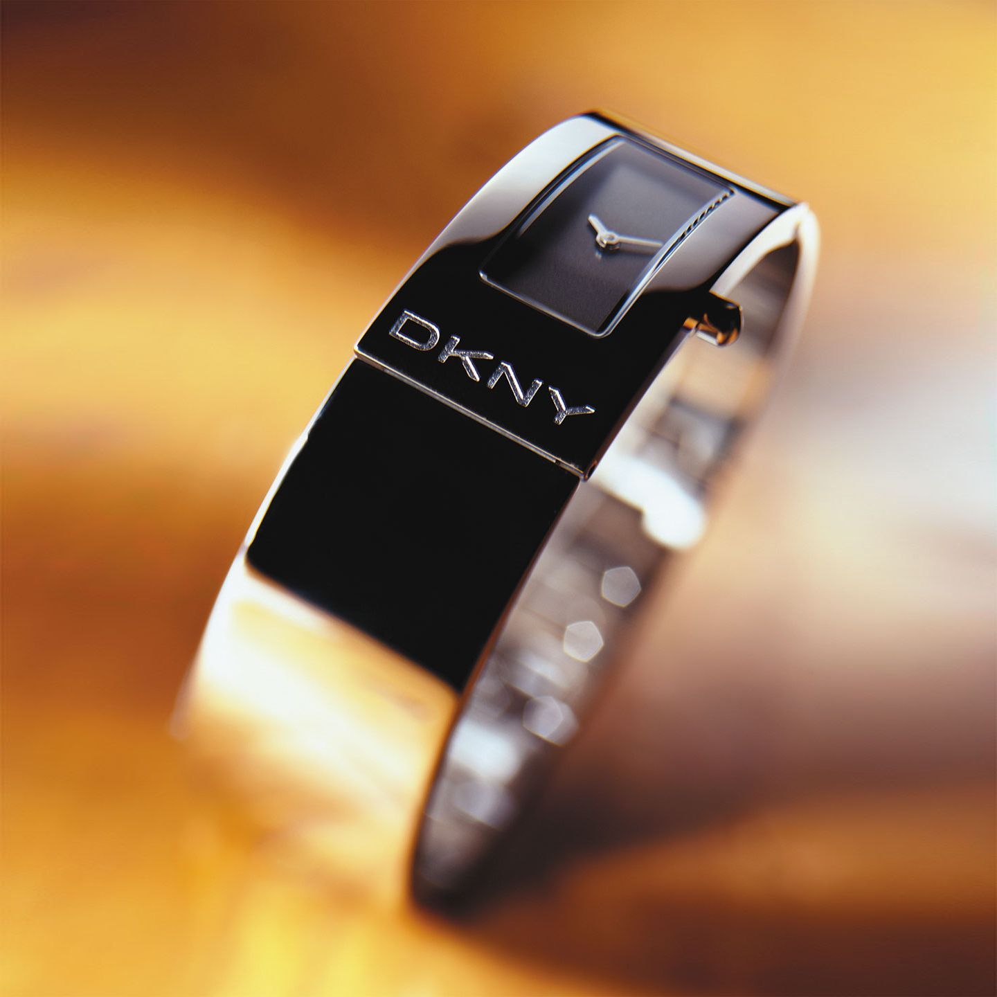DKNY black bangle watch with a rectangular face, reflective.