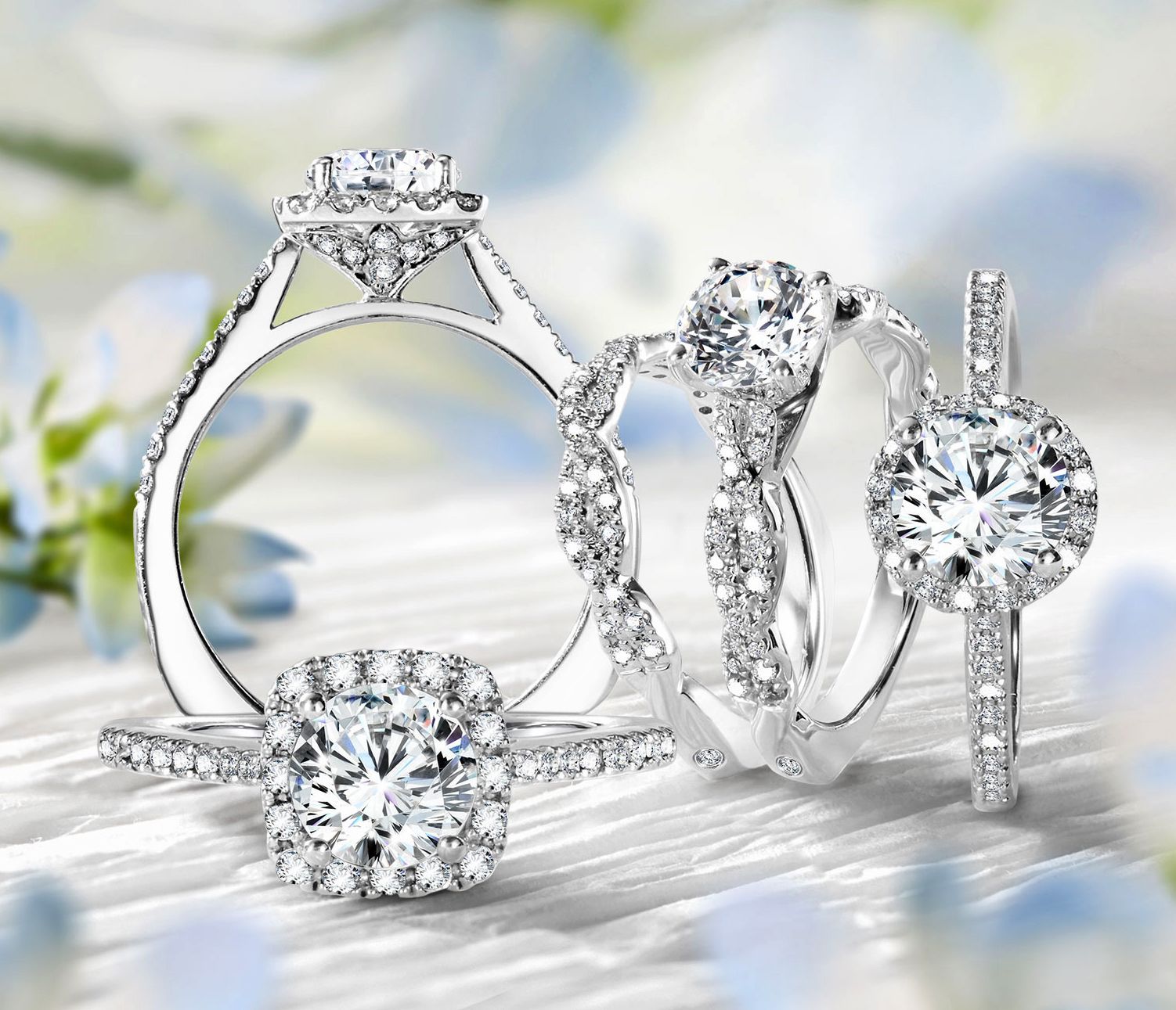Four diamond rings on a light background with blue accents; engagement and wedding rings.