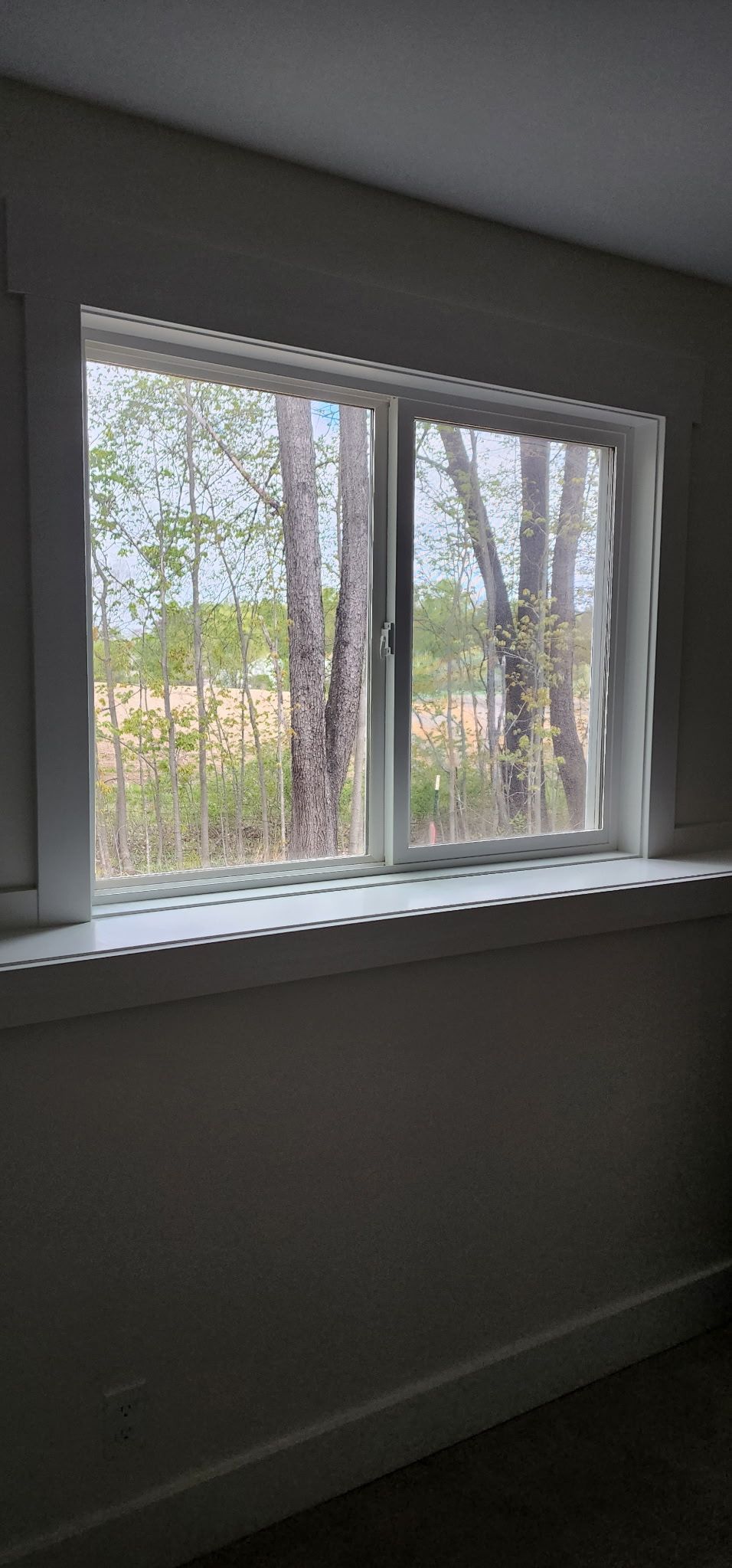 Interior room with a large window, white blinds, and trees visible outside