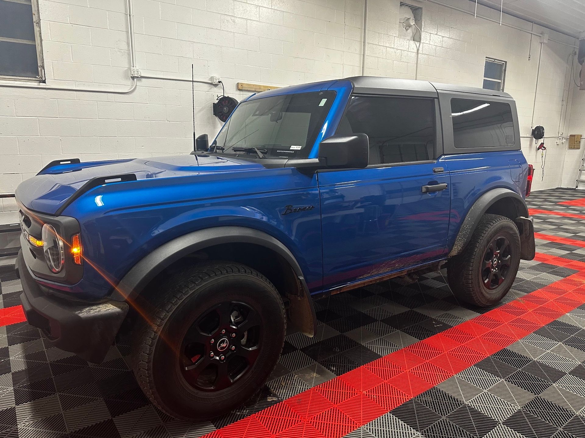 Blue off-road SUV with black rims parked indoors on a checkered floor.