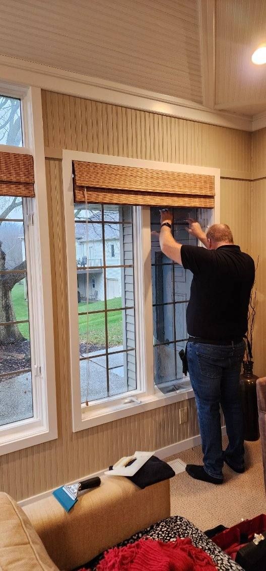 Person hanging a wooden valance above a window in a striped room