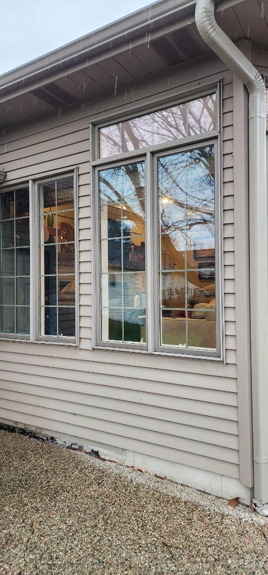 House exterior with beige siding, white-trim windows, and a gravel base under the roof eaves