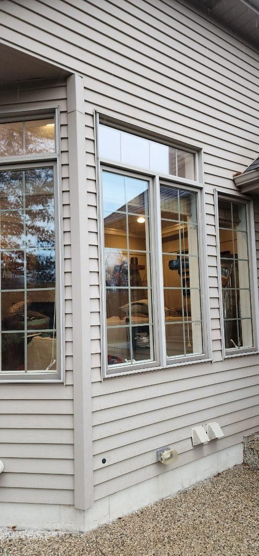 Exterior of a beige house with white-trimmed windows and a gravel foundation