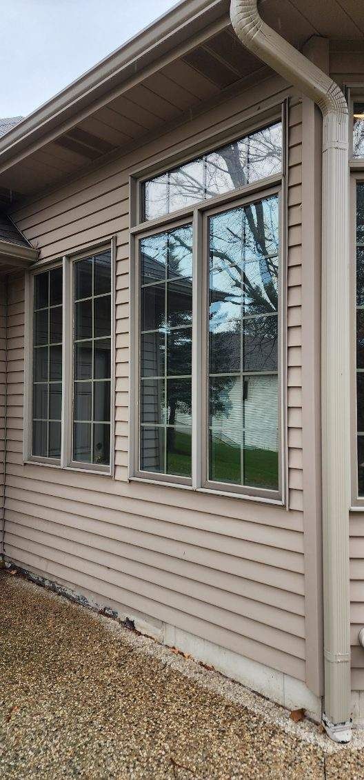 Exterior of a beige house with tall windows and a downspout along the wall