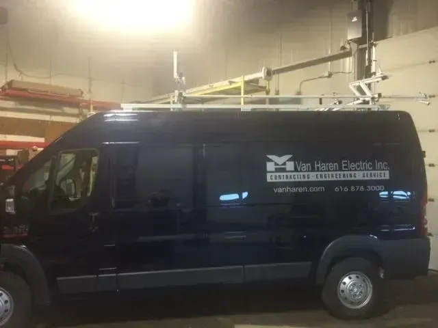 Black Mercedes van with business signage parked in a garage.