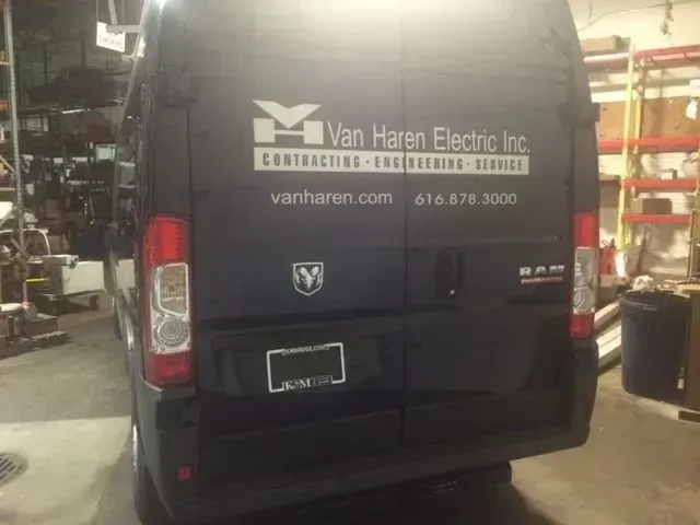Black Van Haren Electric Inc. work van parked in a garage, rear view with company logo and contact info