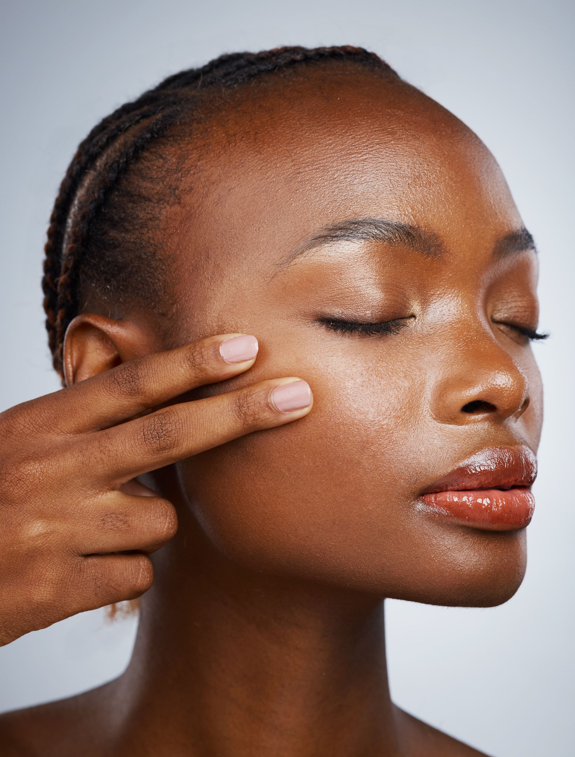 Woman touching her cheek, eyes closed, with glowing skin.