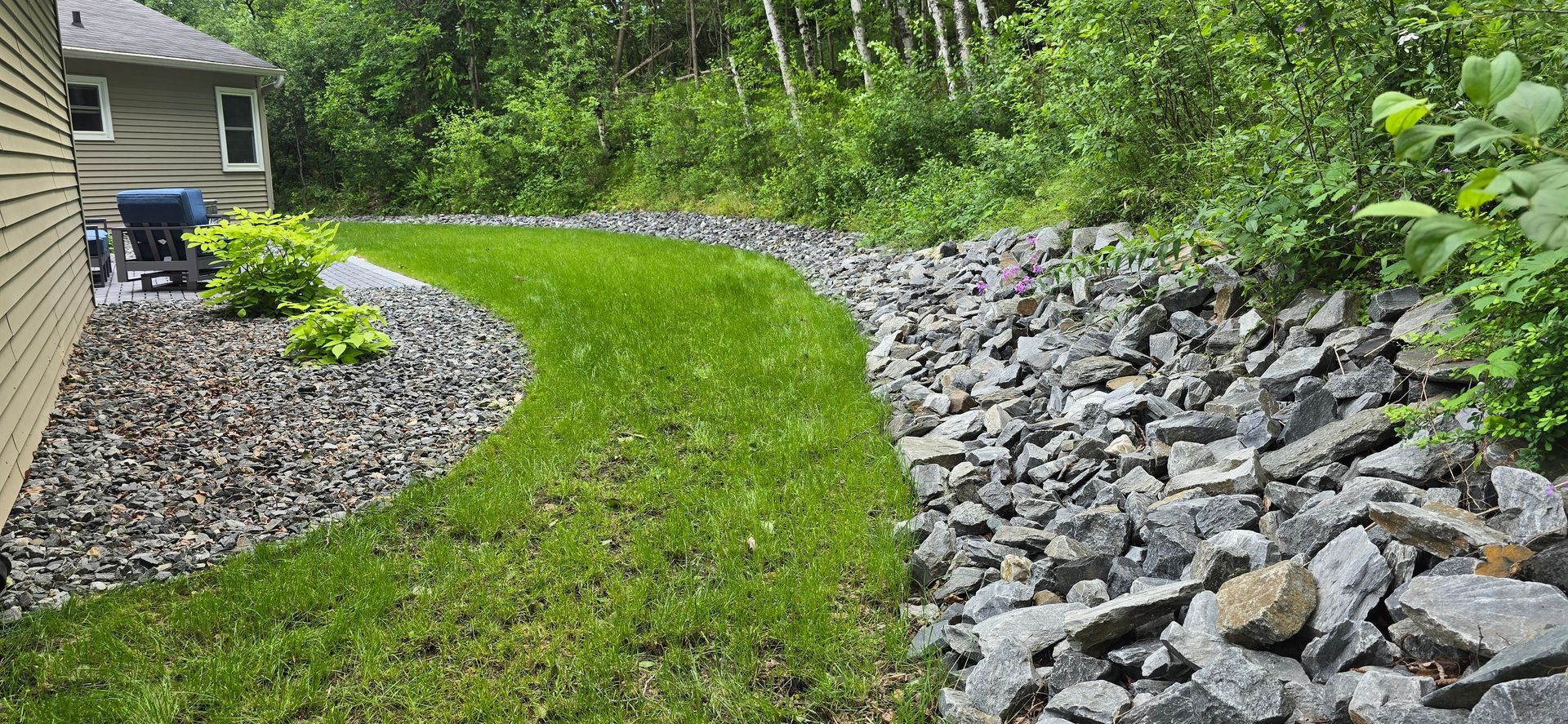 Wausau drainage project with stone border, green lawn, and permeable patio