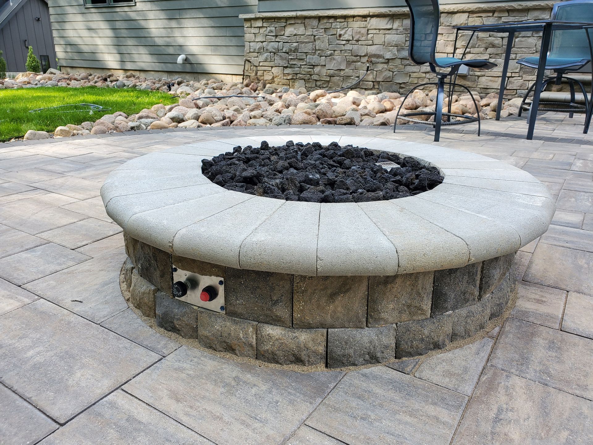 A fire pit is sitting on a patio next to a house.