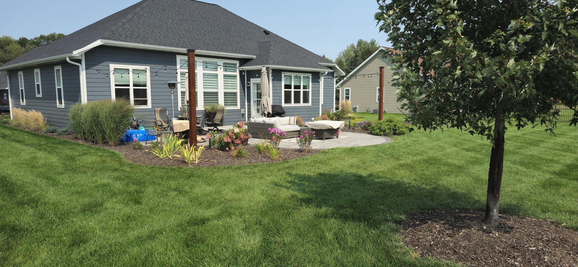 A house with a lush green lawn and a tree in front of it