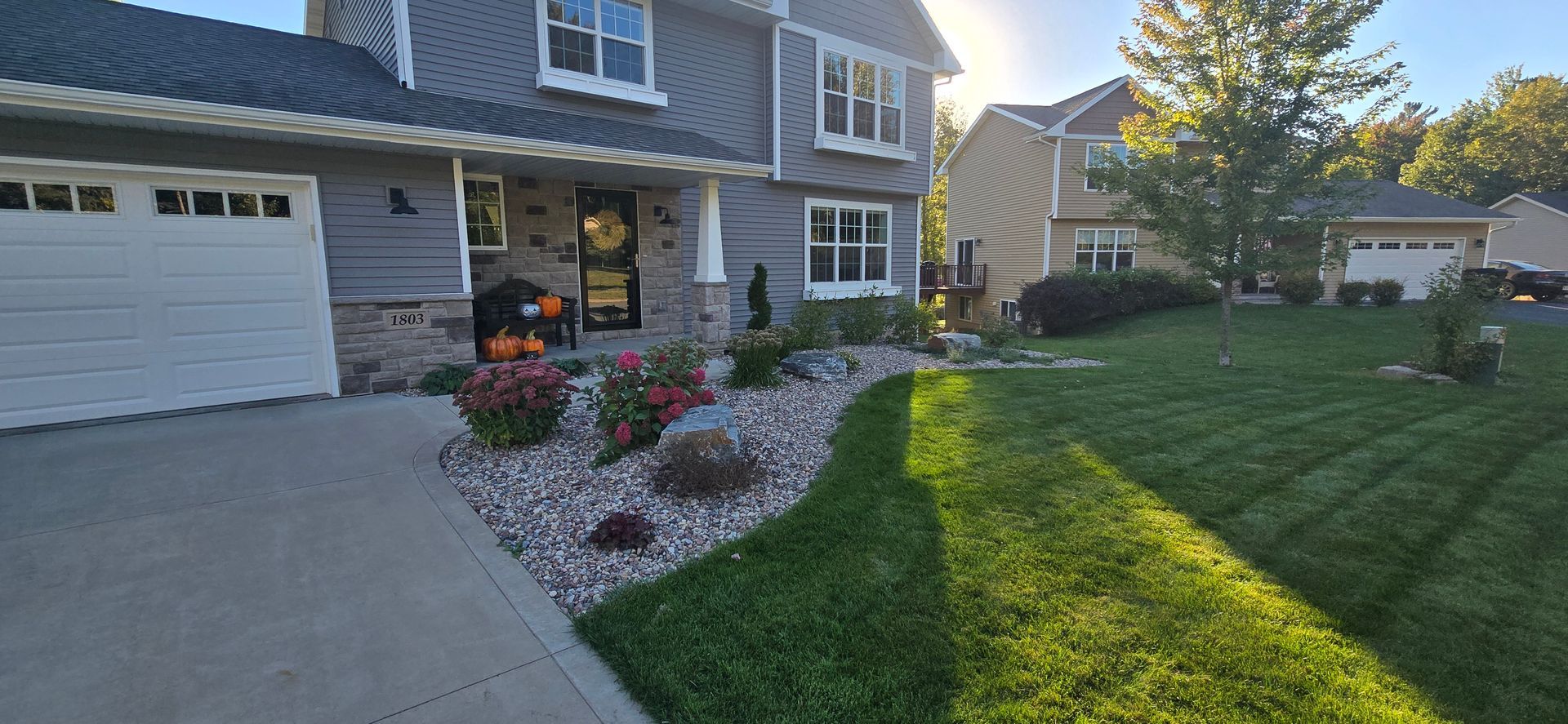 A large house with a newly installed bed with river rock and bushes in Rothschild, Wisconsin