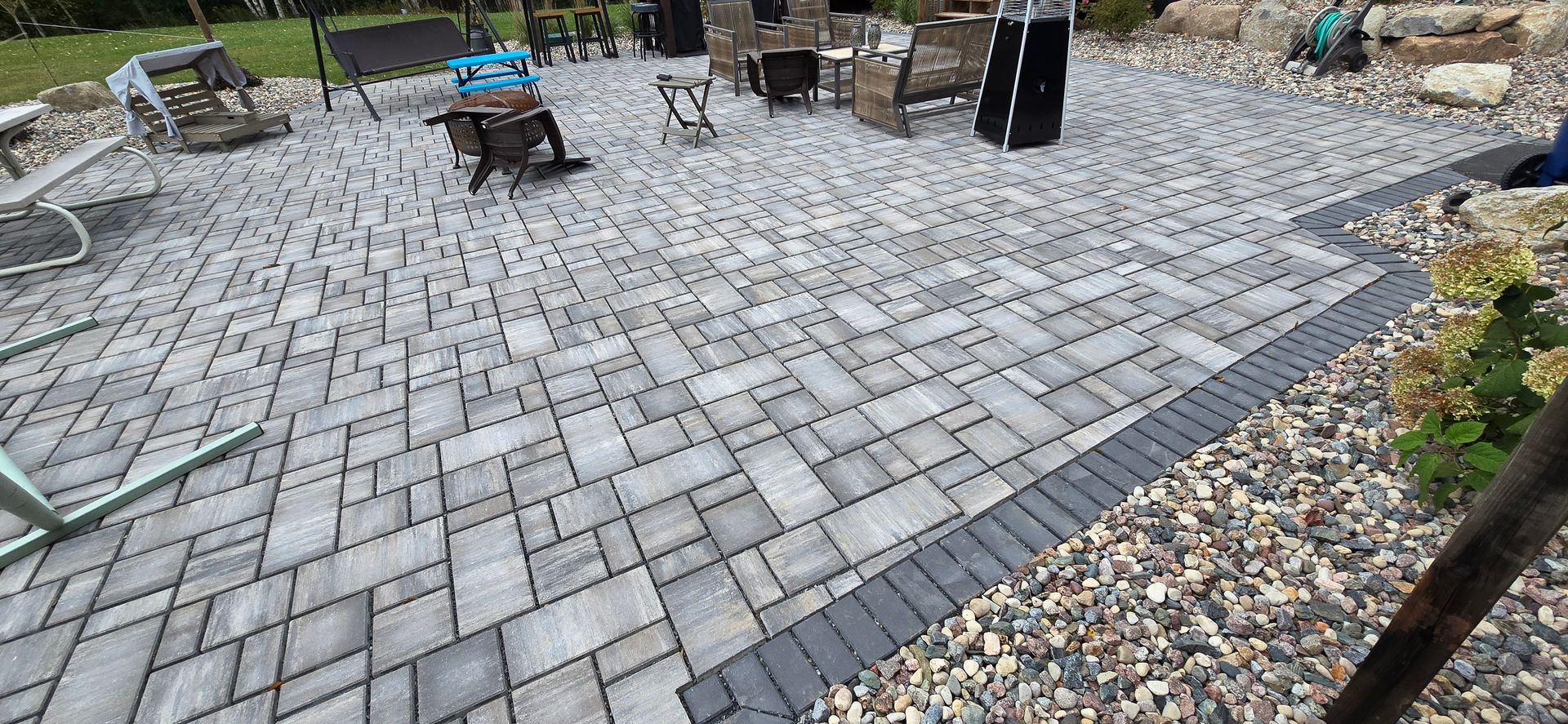 A patio with a brick walkway and gravel in the background.