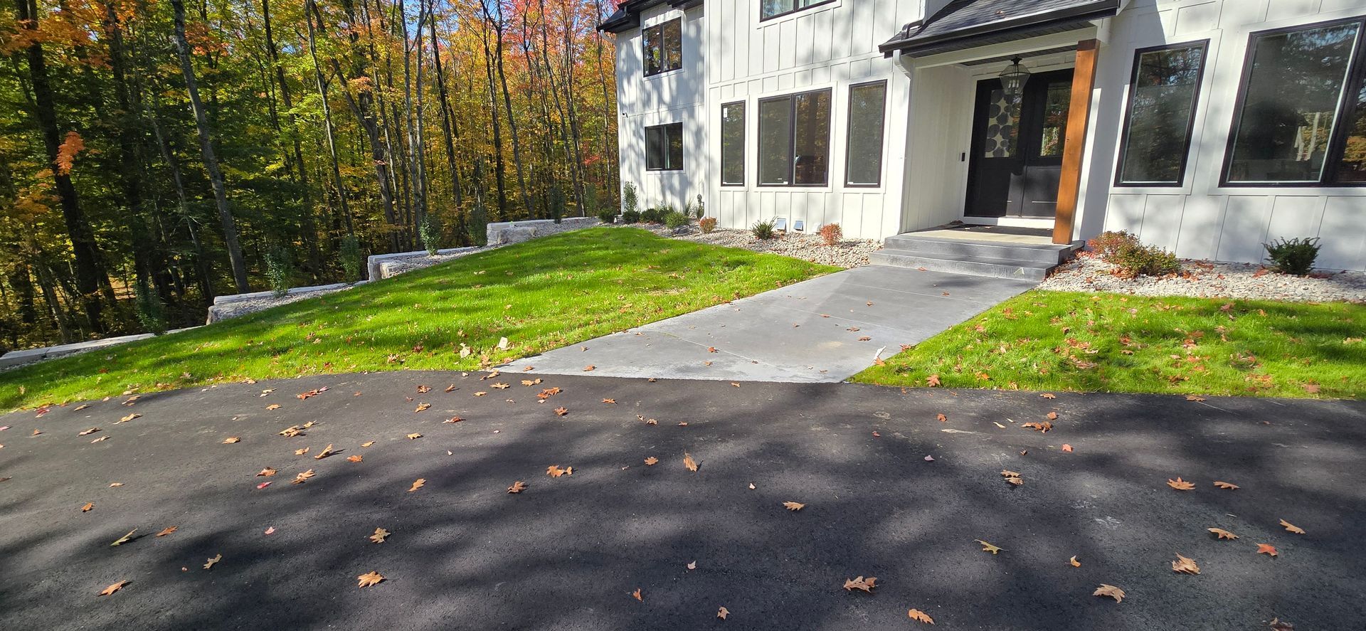 A large white house with a lush green lawn and a driveway leading to it.