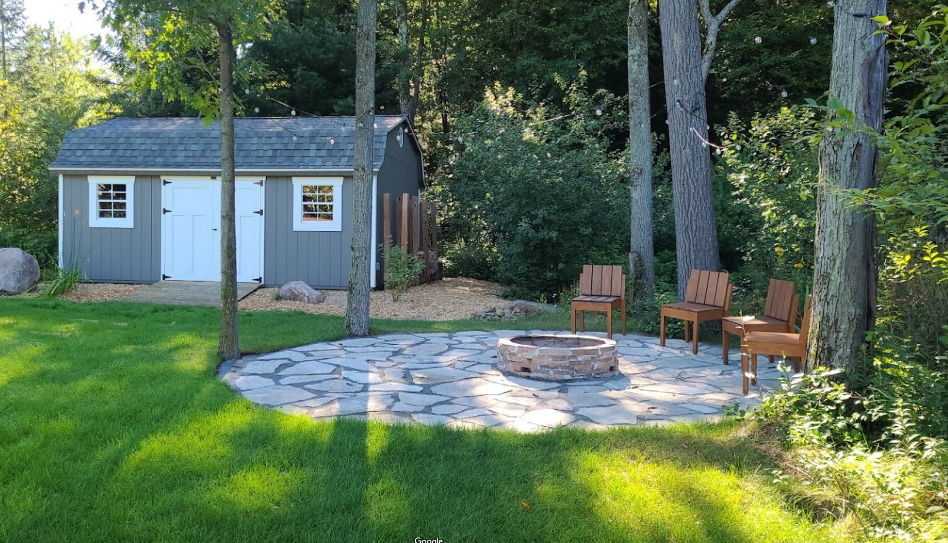 There is a fire pit in the middle of the yard in front of a shed in Schofield, Wisconsin