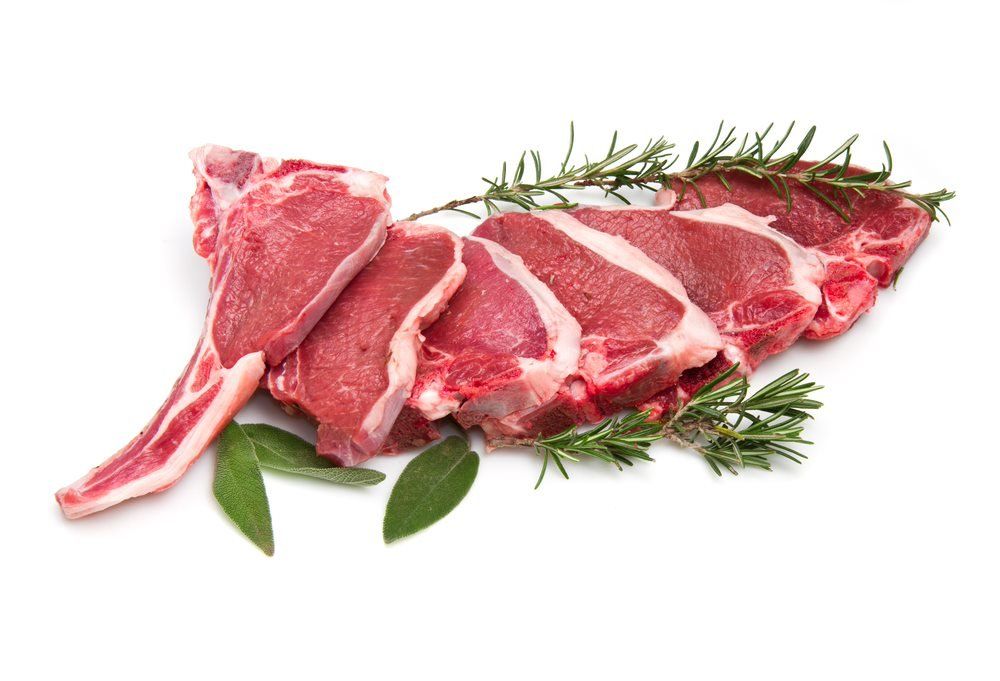Raw lamb chops with rosemary and leaves on a white background.