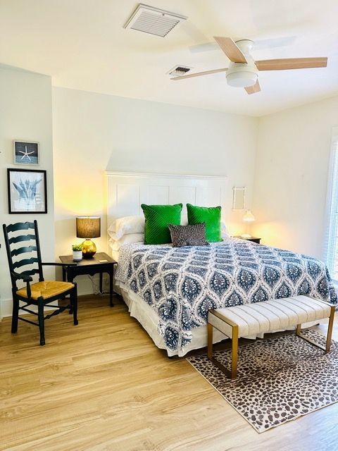A bedroom with a bed , chair , bench and ceiling fan.