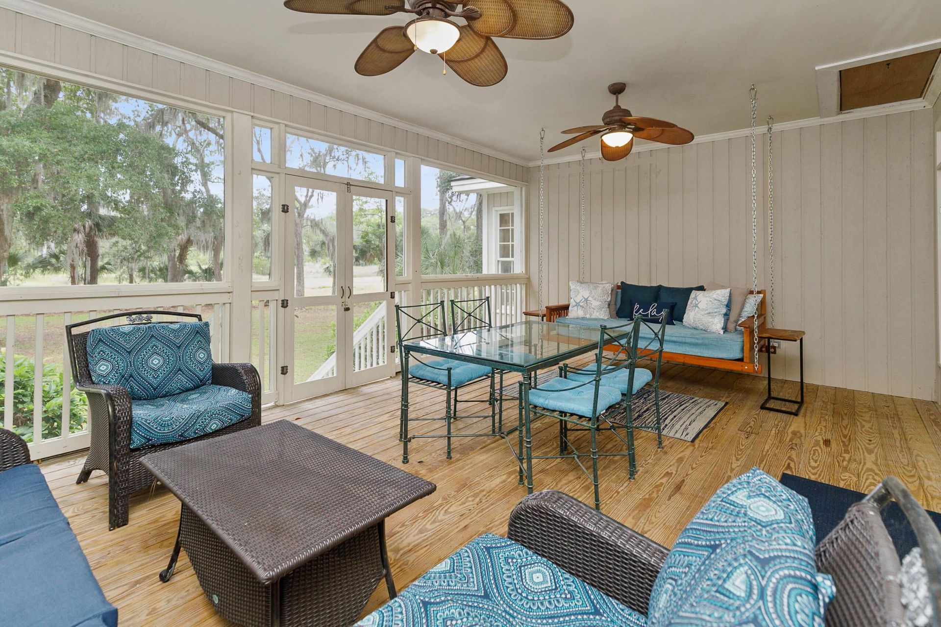 A screened in porch with a table and chairs and a ceiling fan.