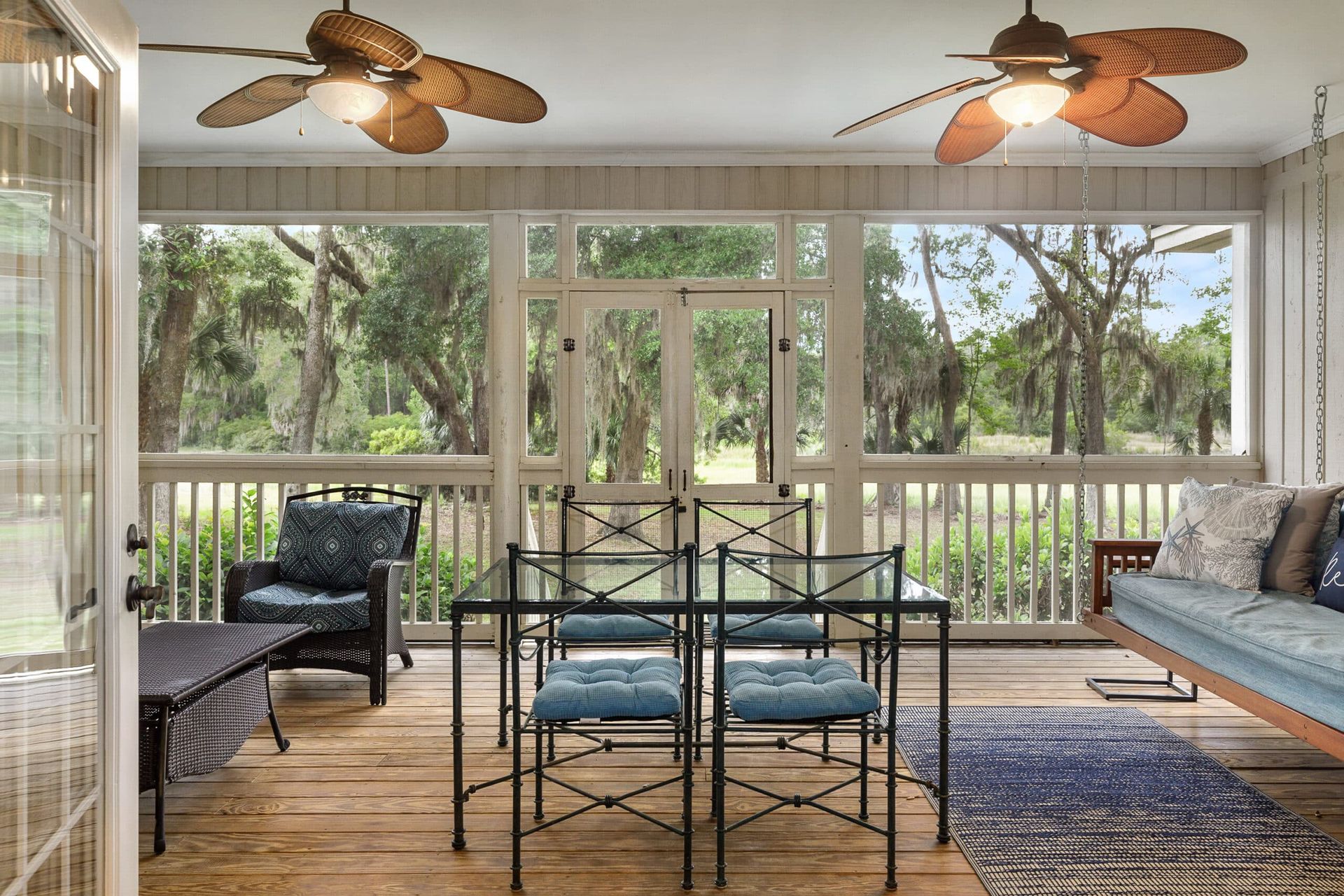 A screened in porch with a table and chairs and ceiling fans.