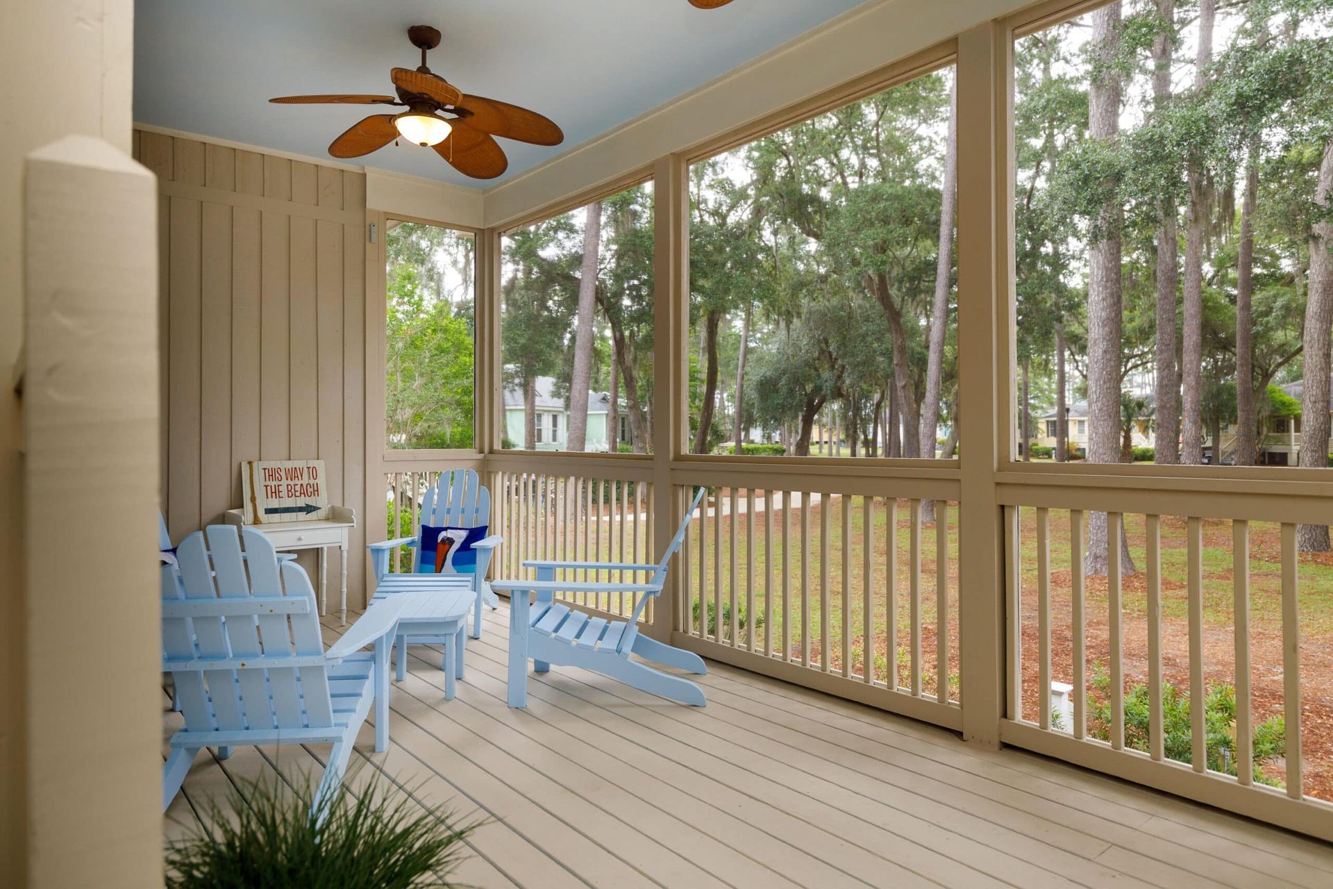 A screened in porch with blue chairs and a ceiling fan
