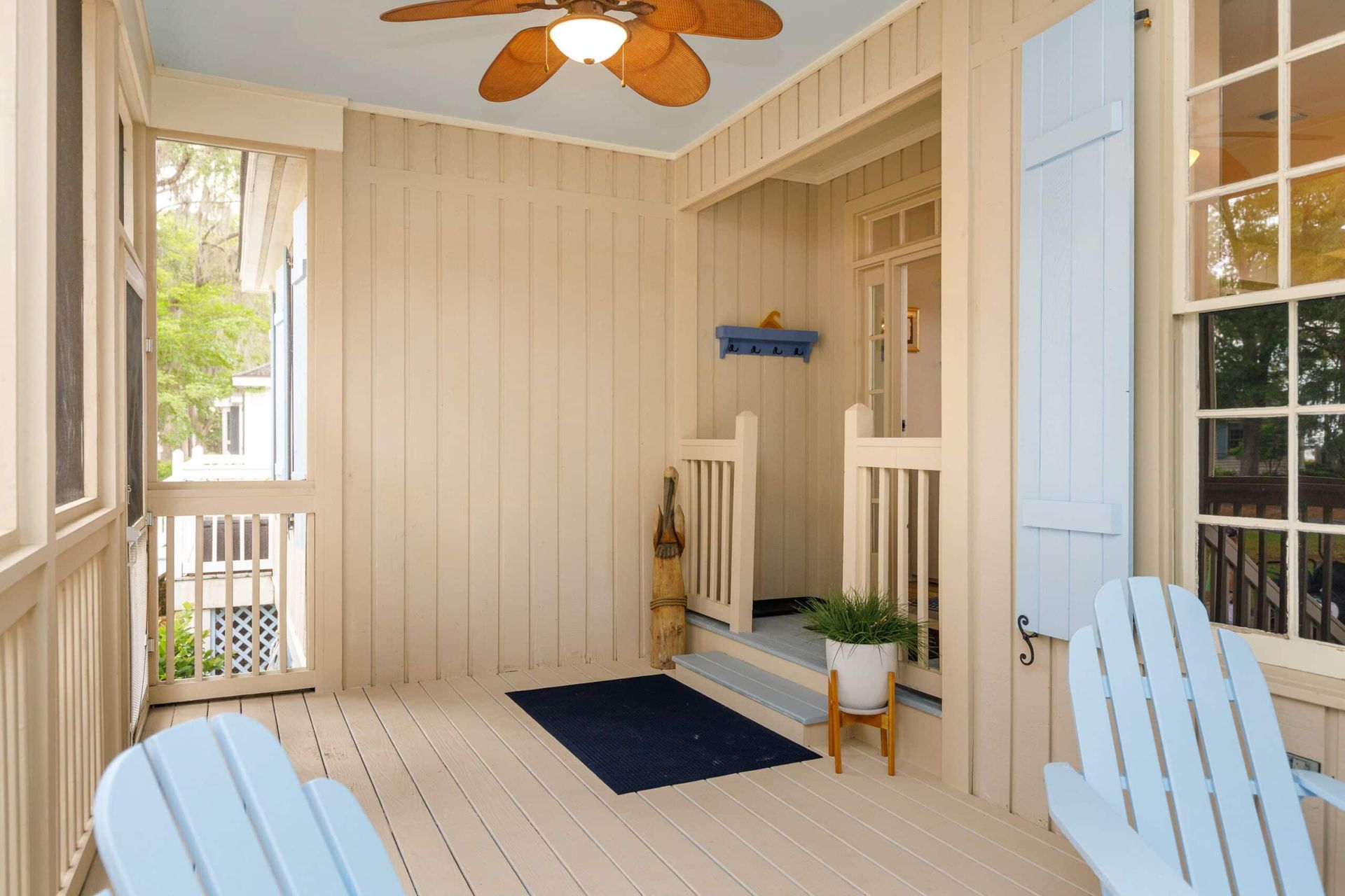 A screened in porch with two blue chairs and a ceiling fan