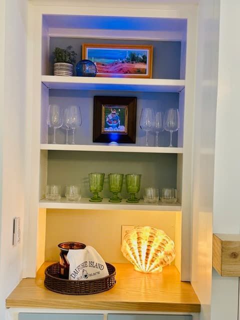 A shelf with wine glasses and a picture on it.