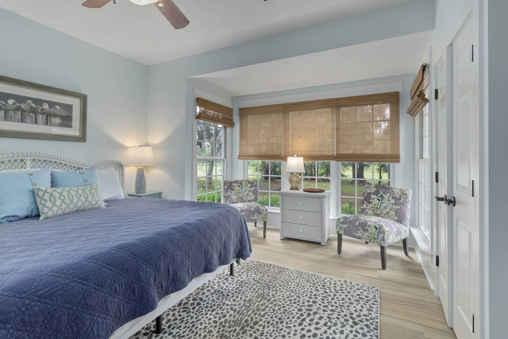A bedroom with a bed , chairs , lamps and a ceiling fan.