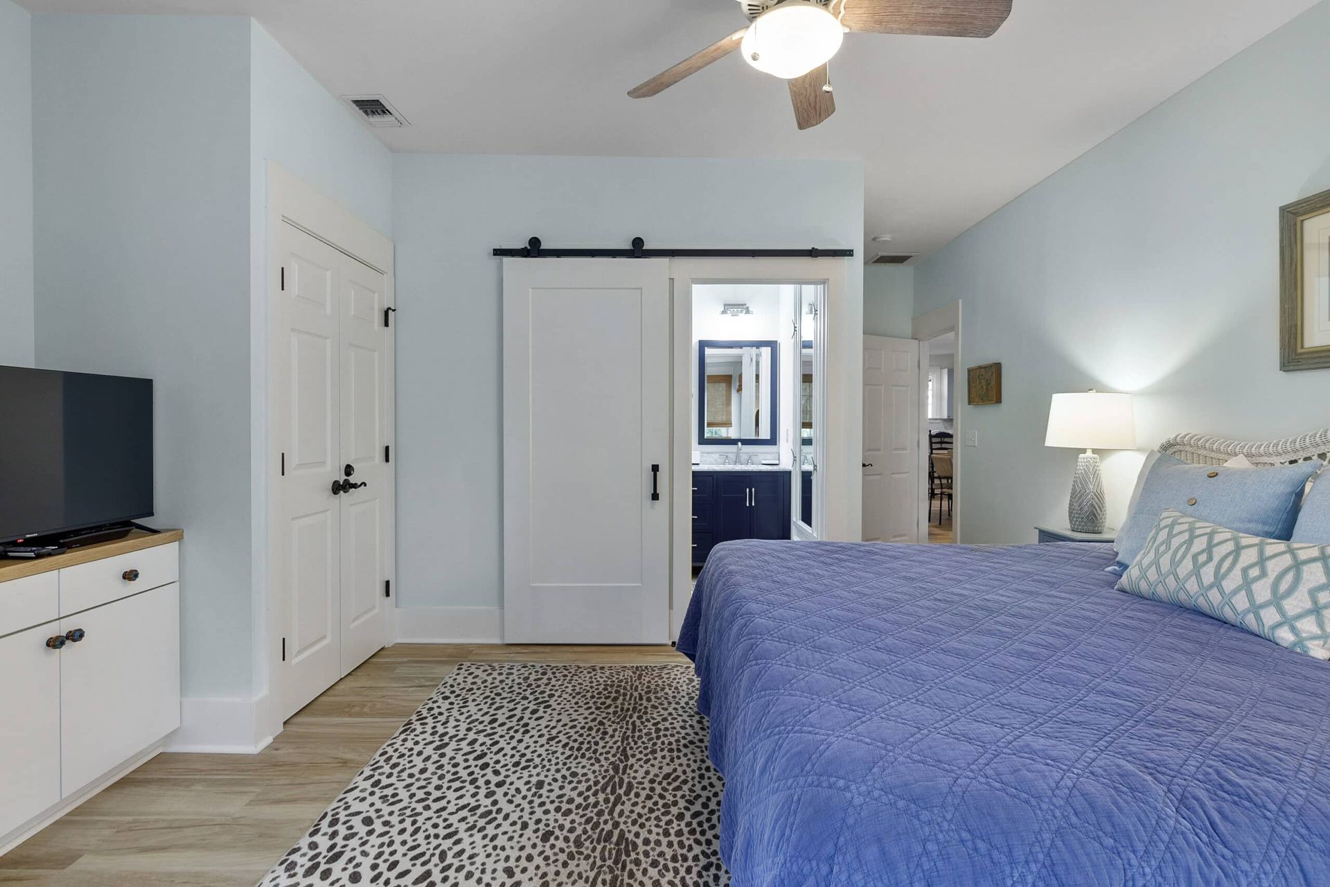 A bedroom with a king size bed , television , and ceiling fan.