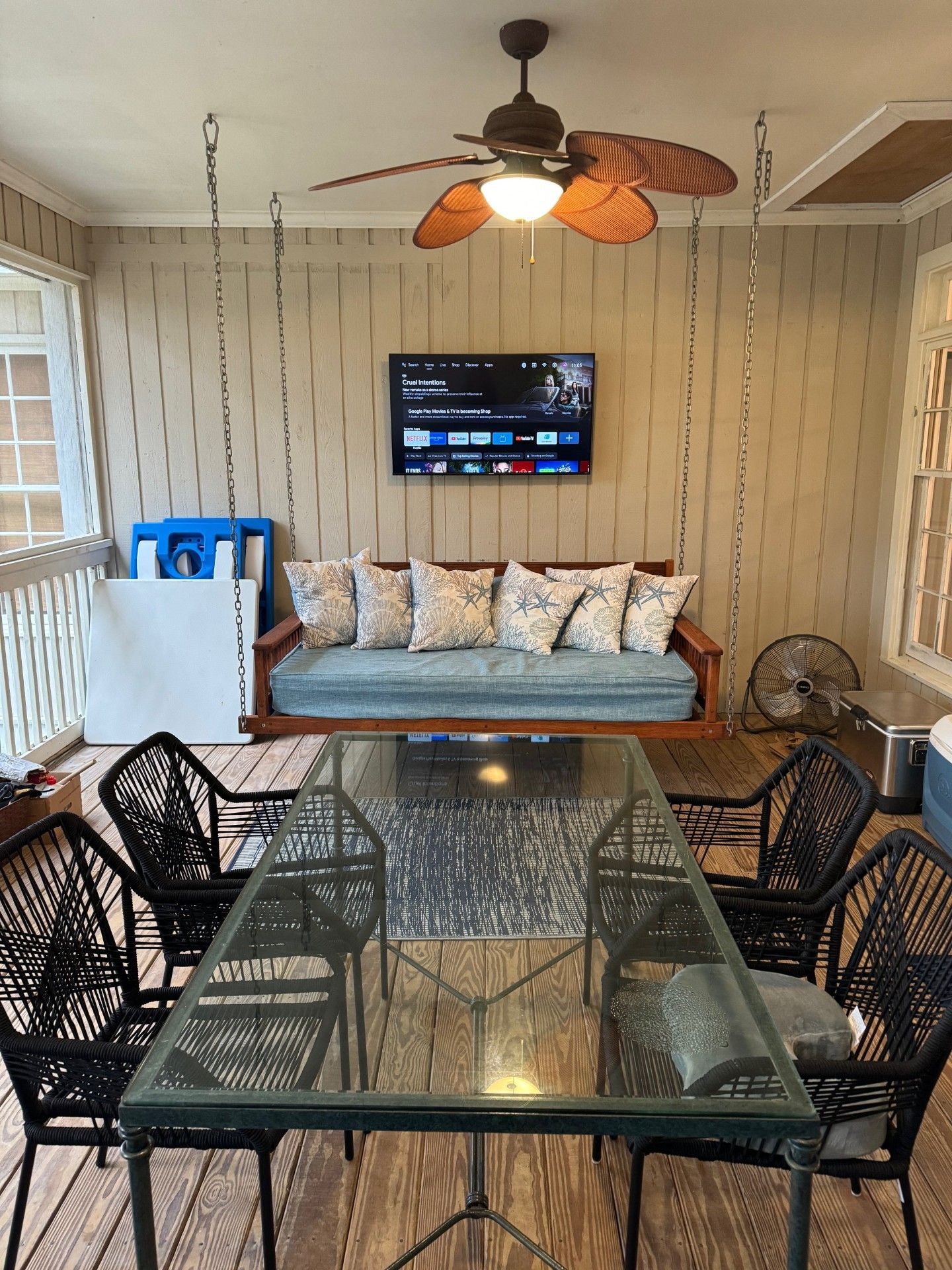 A living room with a couch , table , chairs and a ceiling fan.