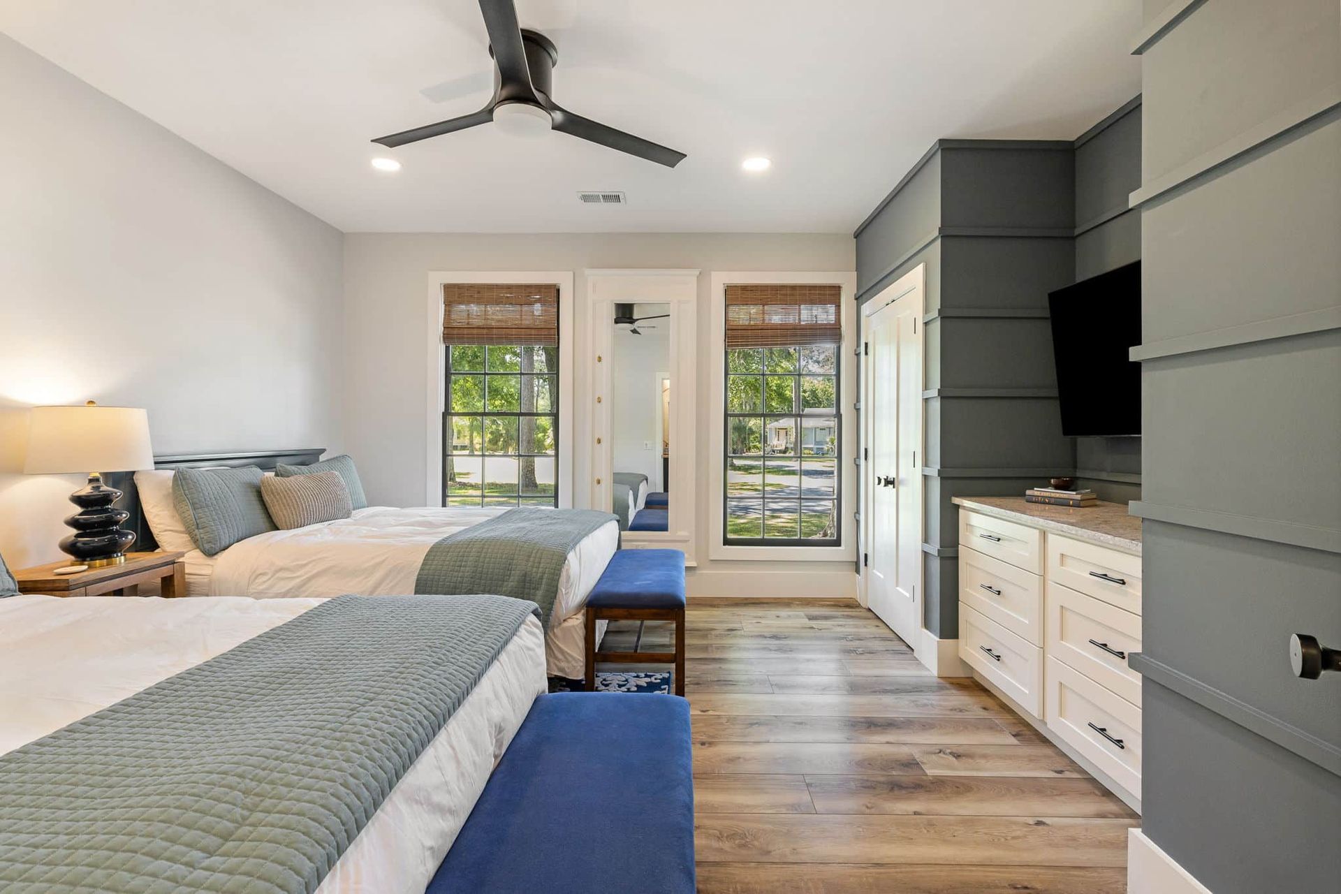 A bedroom with two beds , a ceiling fan and a television.