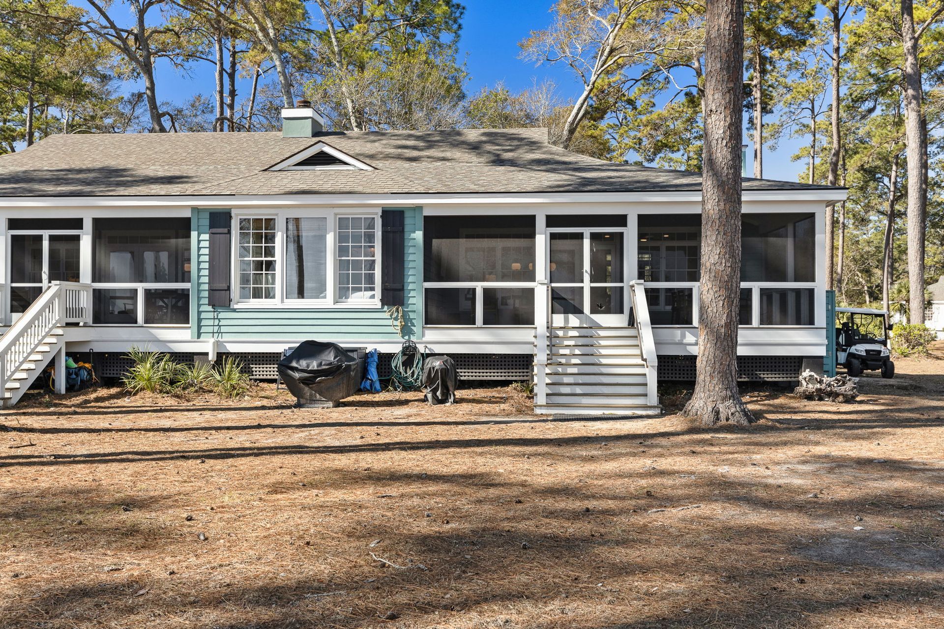 A house with a screened in porch and a golf cart parked in front of it.