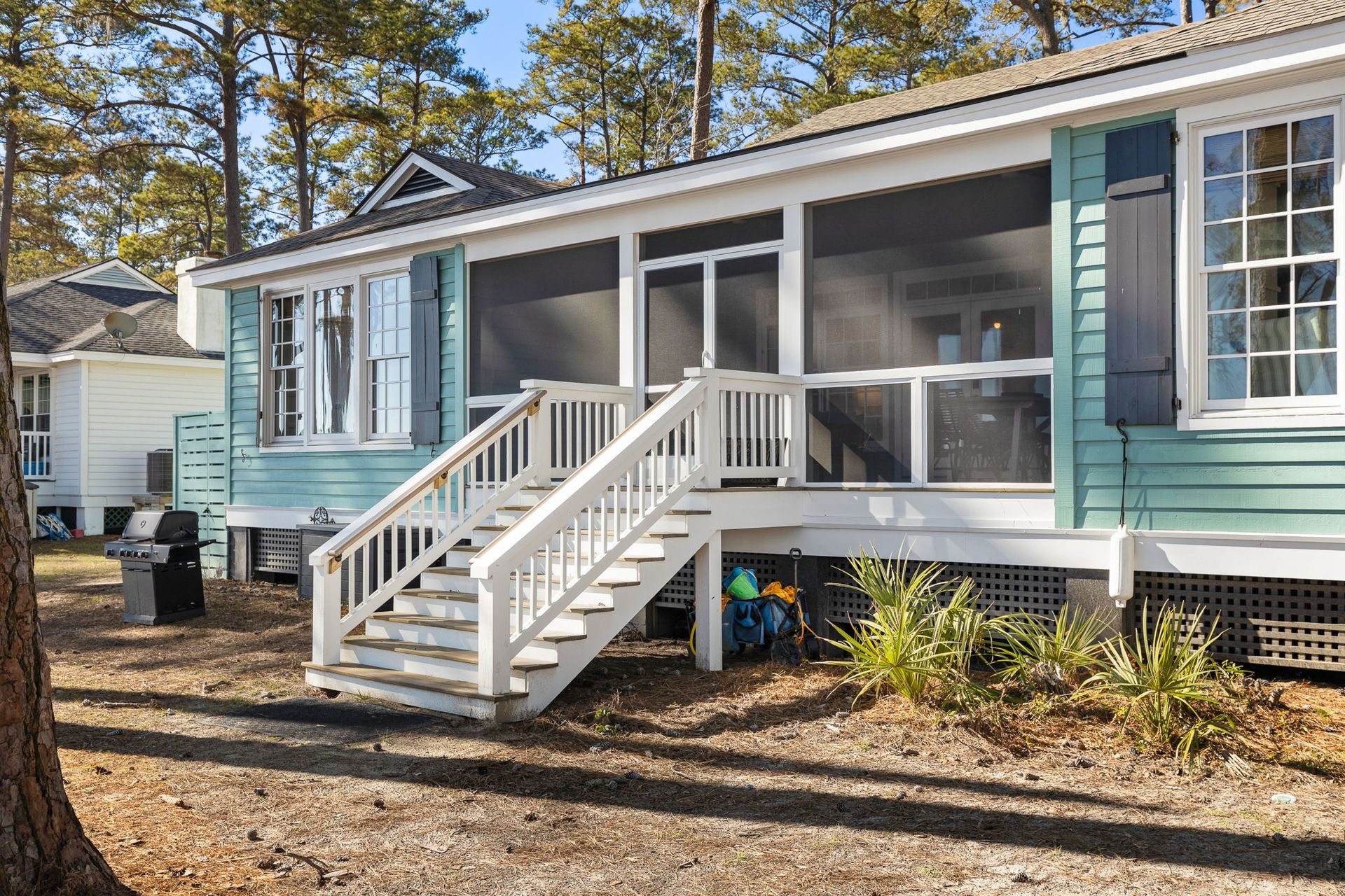 A blue and white house with a screened in porch and stairs.