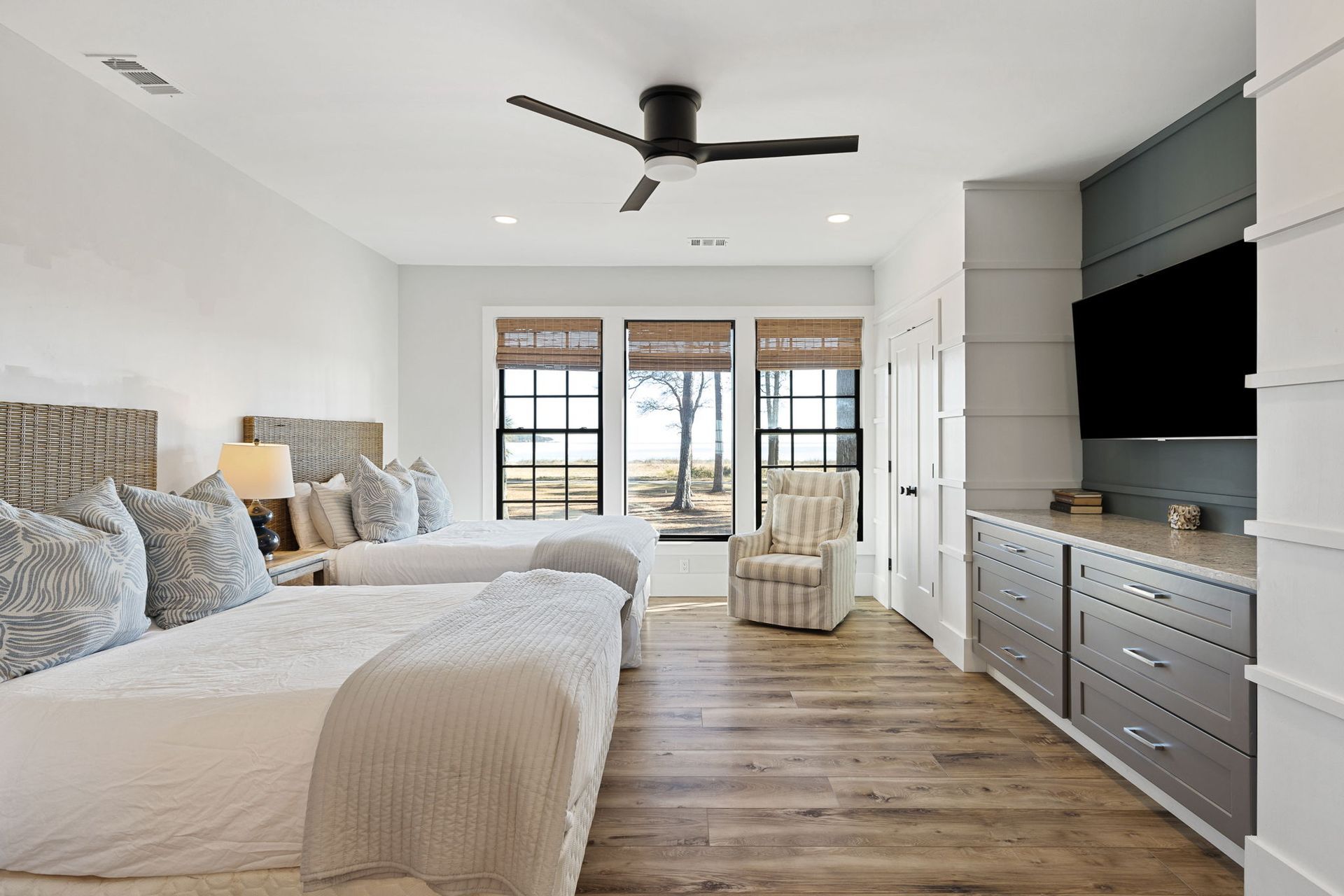 A bedroom with two beds , a chair , a television and a ceiling fan.