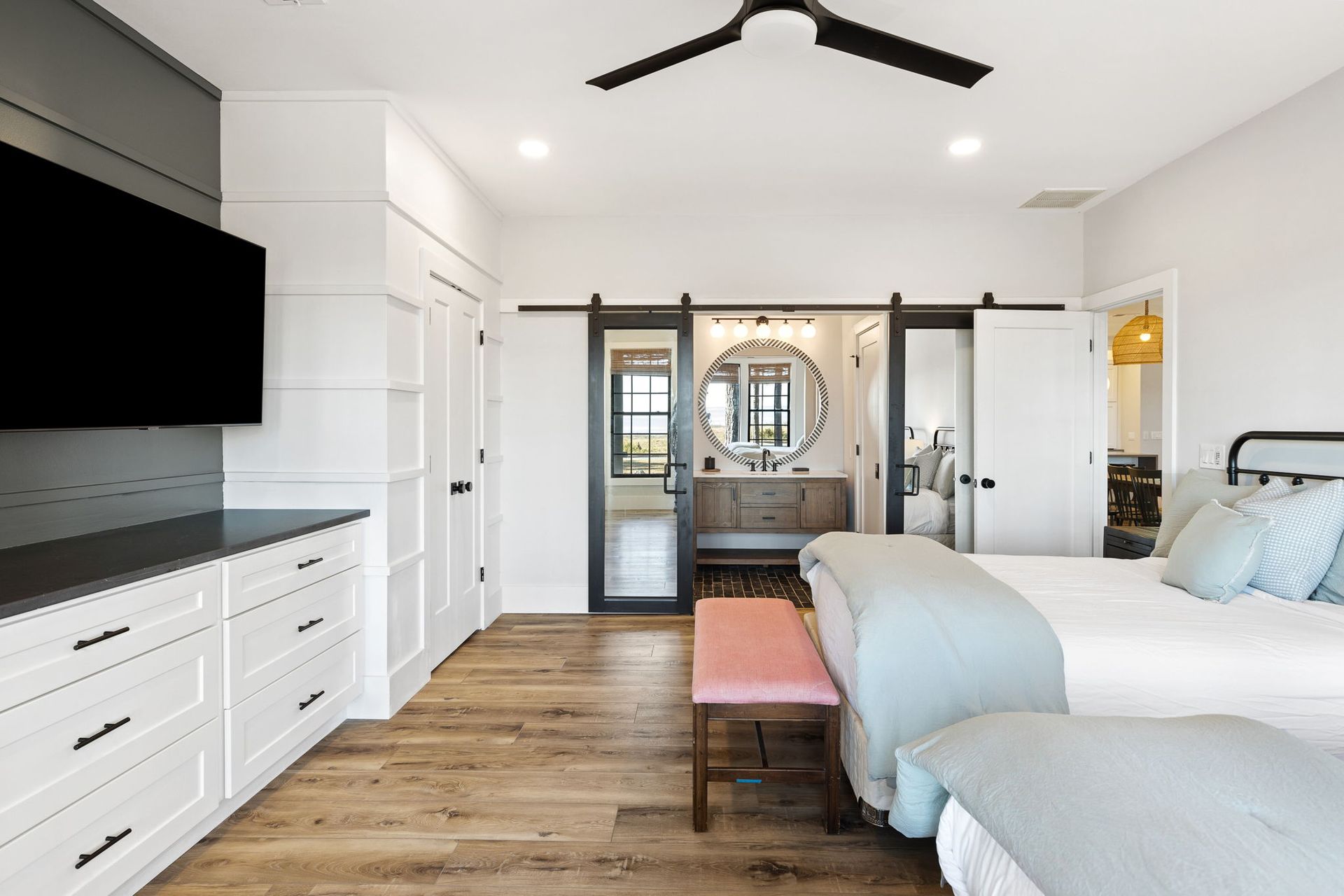 A bedroom with two beds , a television and a ceiling fan.
