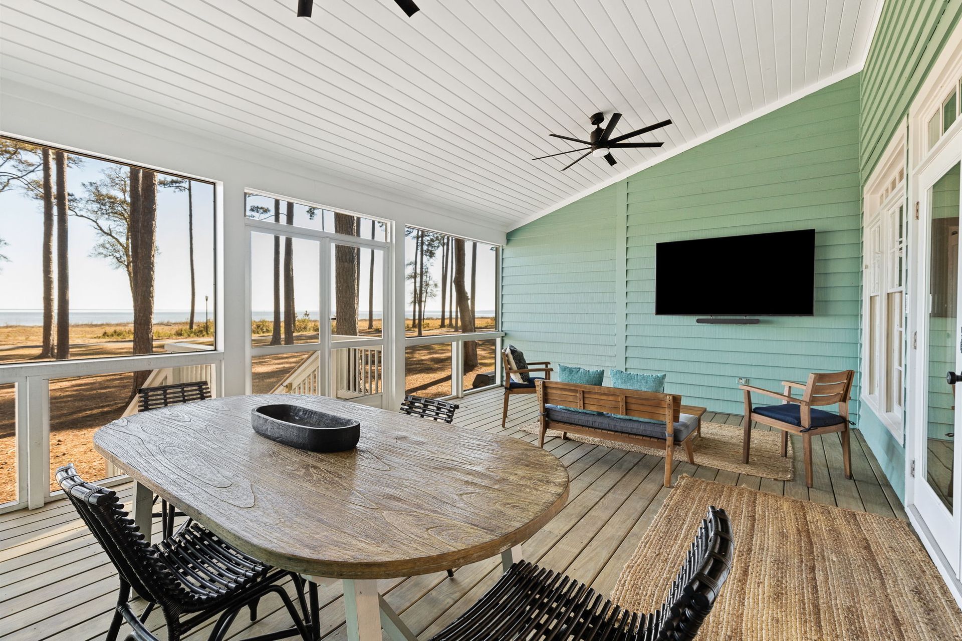 A screened in porch with a table and chairs and a flat screen tv.