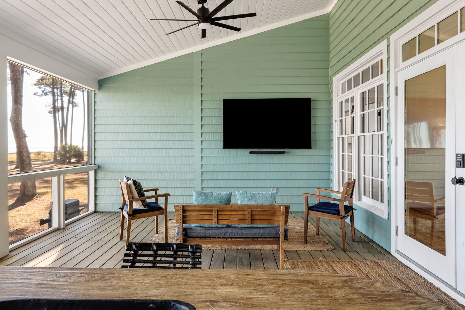A screened in porch with a flat screen tv on the wall.