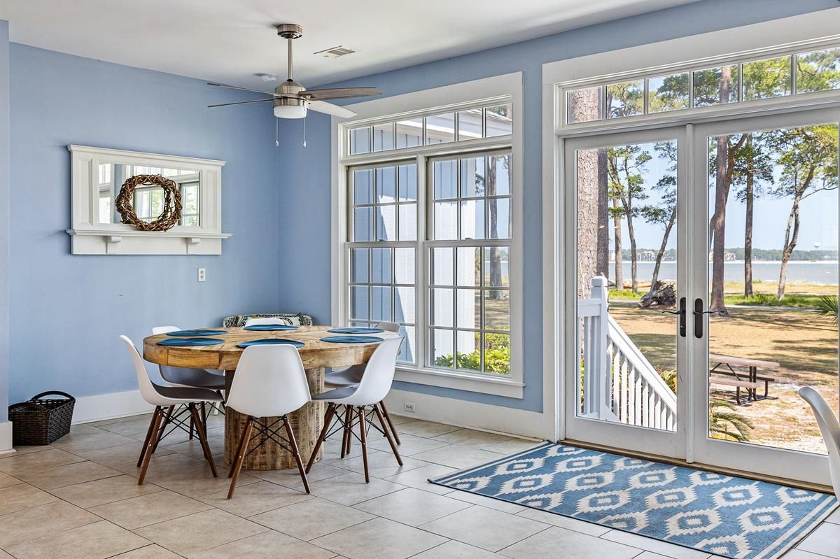 A dining room with a table and chairs and a view of the ocean.