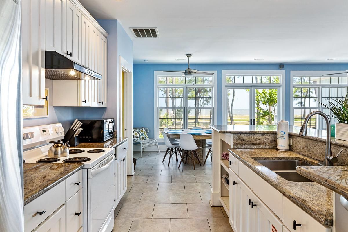 A kitchen with white cabinets , granite counter tops , a sink and a stove.