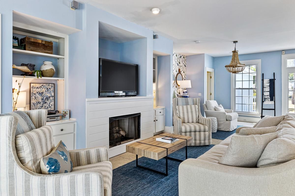 A living room with a couch , chairs , a fireplace and a flat screen tv.