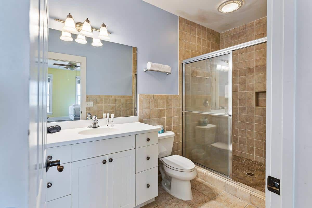 A bathroom with a toilet , sink , mirror and shower.