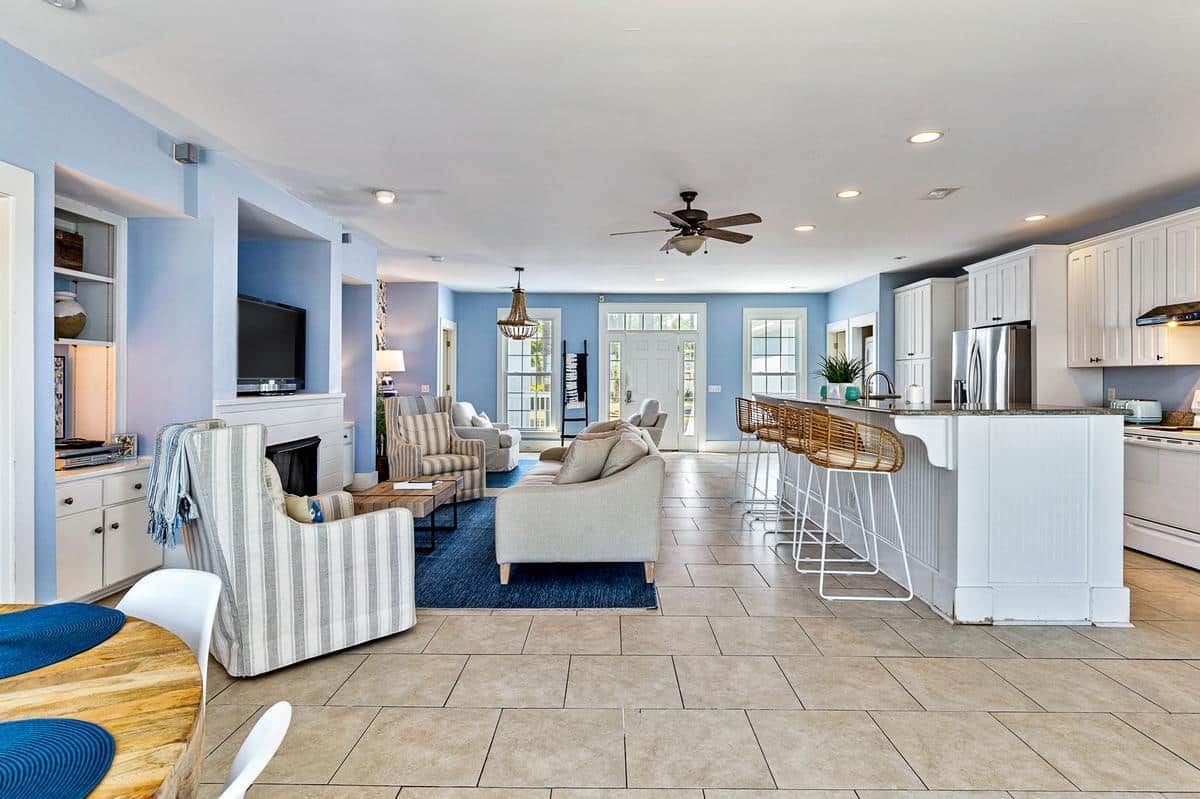 A living room and kitchen in a house with a ceiling fan.