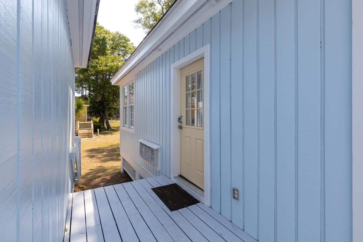A blue house with a yellow door and a white porch.