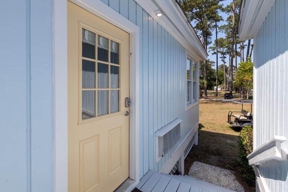 A yellow door is on the side of a blue house.