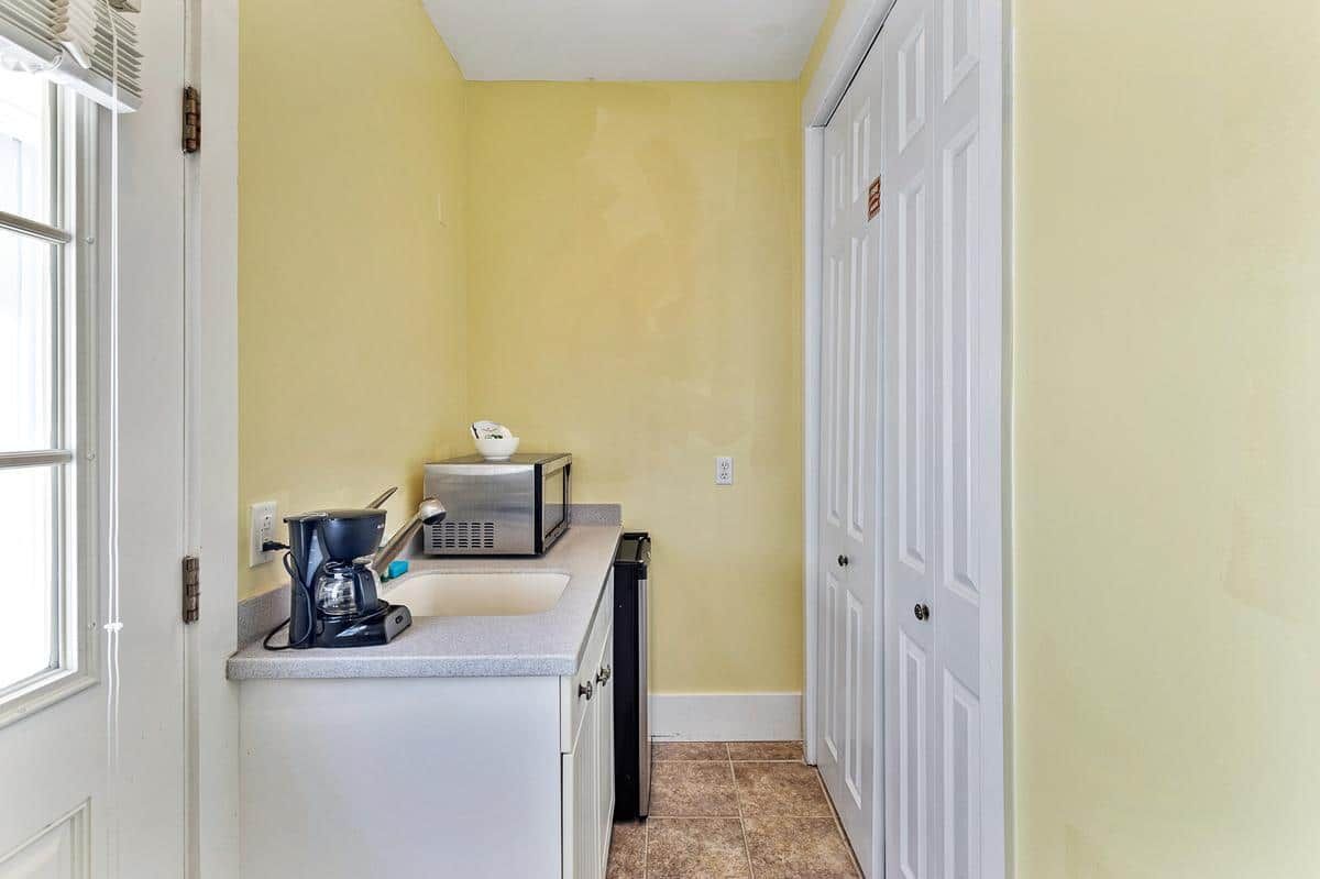 A kitchen with a sink , microwave , and coffee maker.