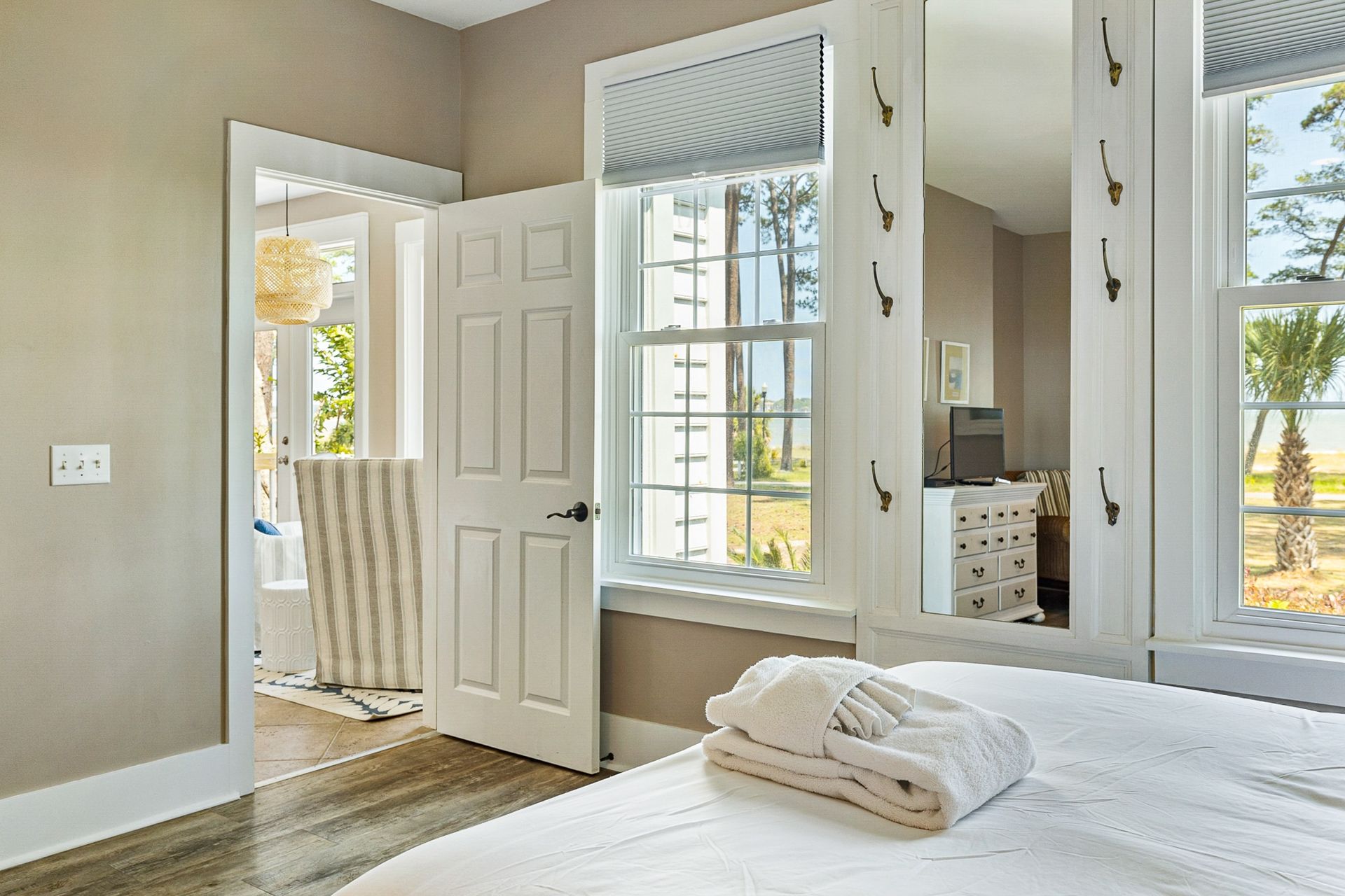 A bedroom with a bed , a window , a mirror and a dresser.