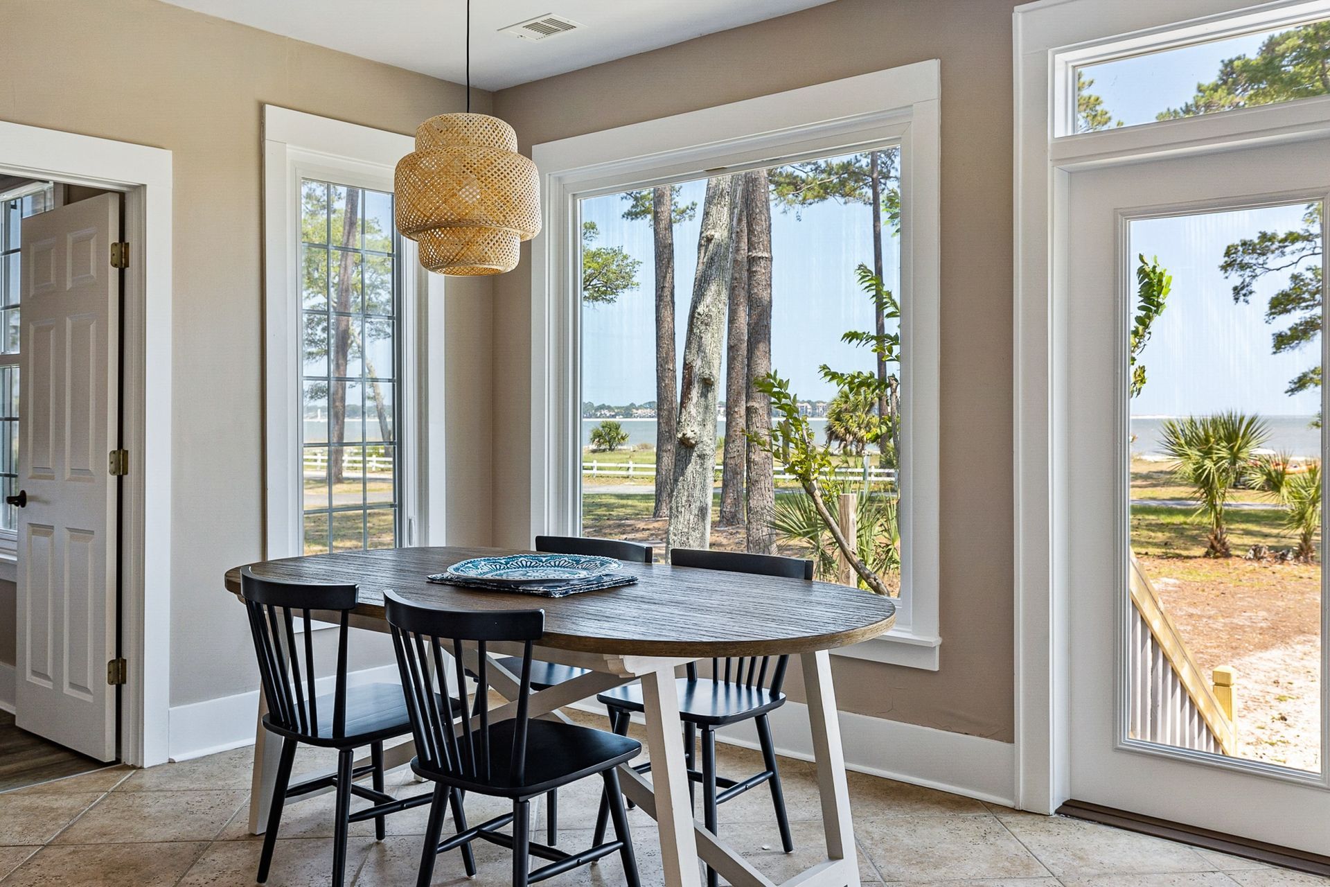 A dining room with a table and chairs and a view of the ocean.